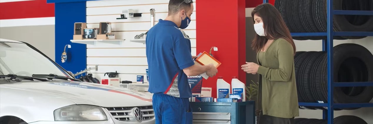 Três mecânicos conversando com os produtos da Acdelco na frente